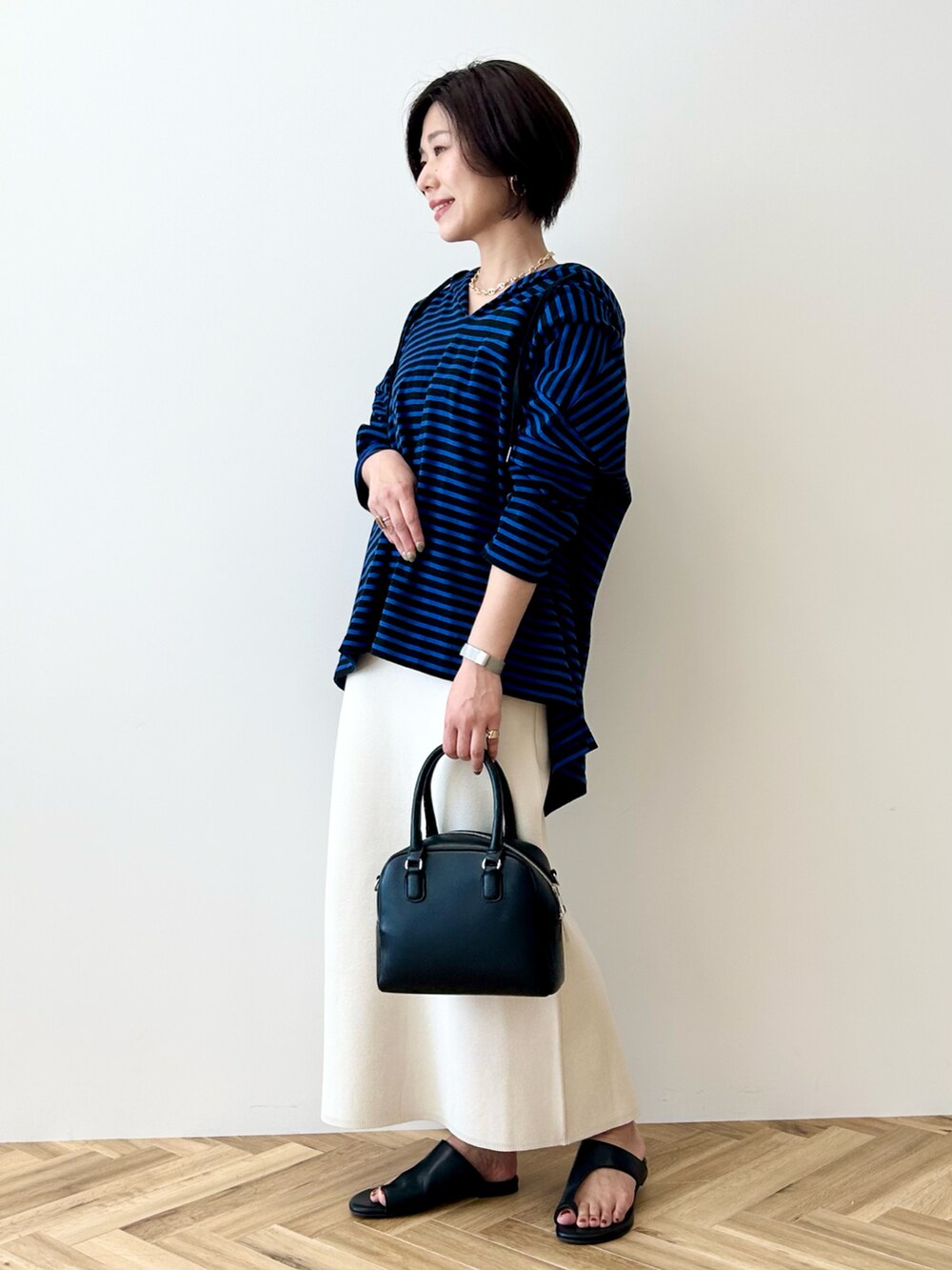 ブルー系のチュニック、ホワイト系のスカート、ブラック系のボストンバッグを着用したレディースの春コーディネートの3枚目の写真