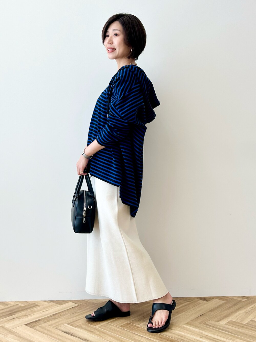 ブルー系のチュニック、ホワイト系のスカート、ブラック系のボストンバッグを着用したレディースの春コーディネートの4枚目の写真