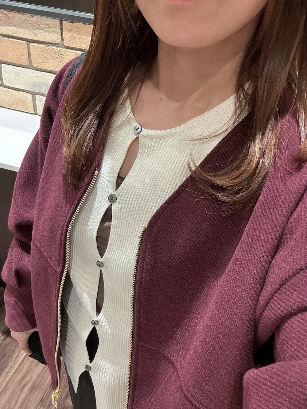 レッド系のブルゾン、ホワイト系のニット/セーター、ブラウン系のキャミソールを着用したレディースの秋コーディネートの2枚目の写真