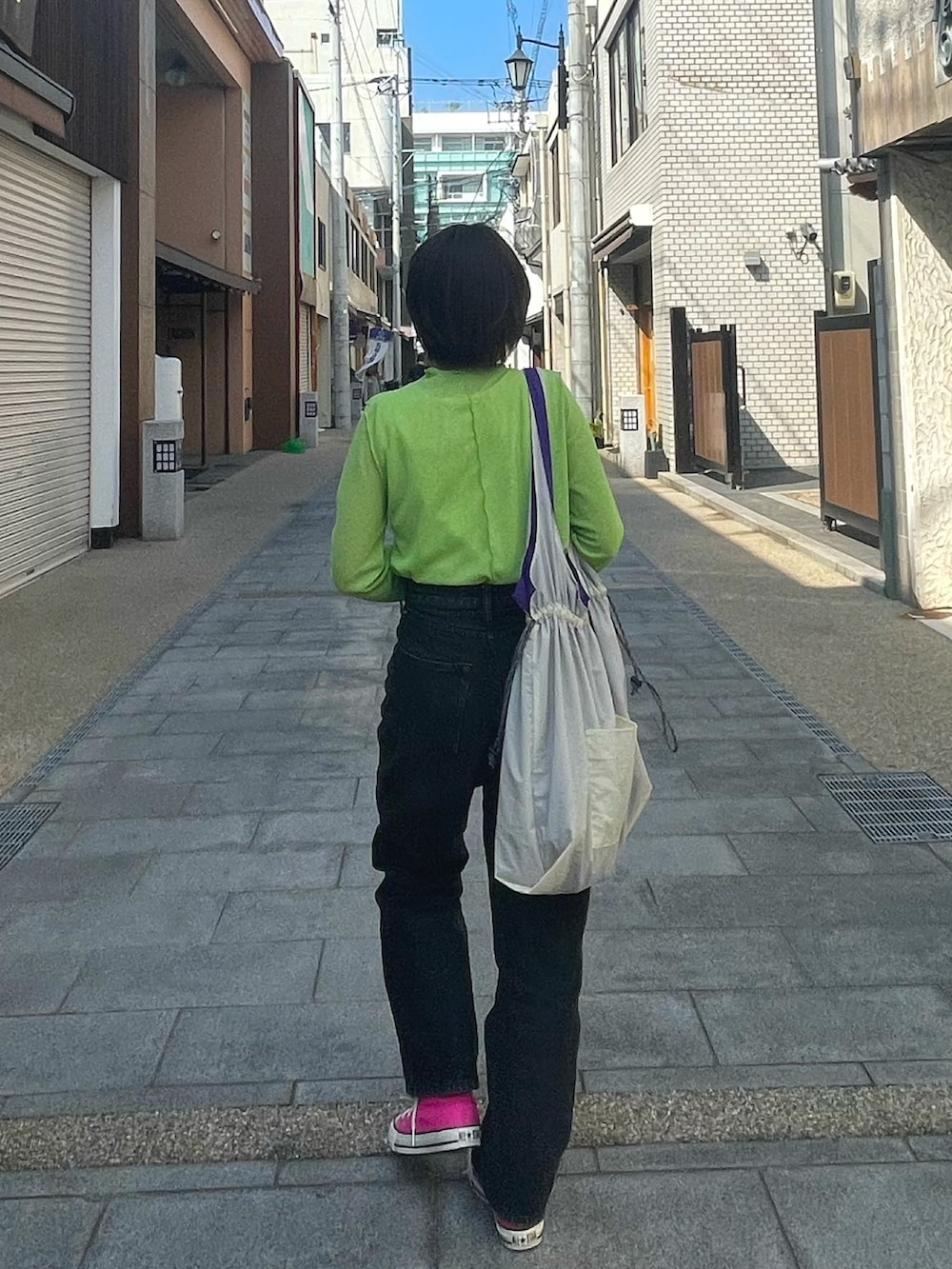 ブラック系のスニーカー、グリーン系のトップス、ブラック系のデニムパンツを着用したレディースの春コーディネートの3枚目の写真