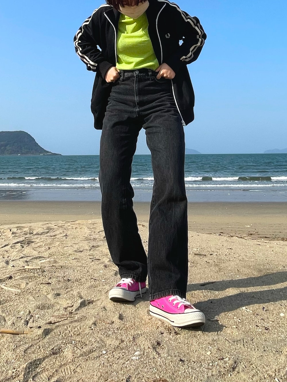 ブラック系のスニーカー、グリーン系のトップス、ブラック系のデニムパンツを着用したレディースの春コーディネートの2枚目の写真