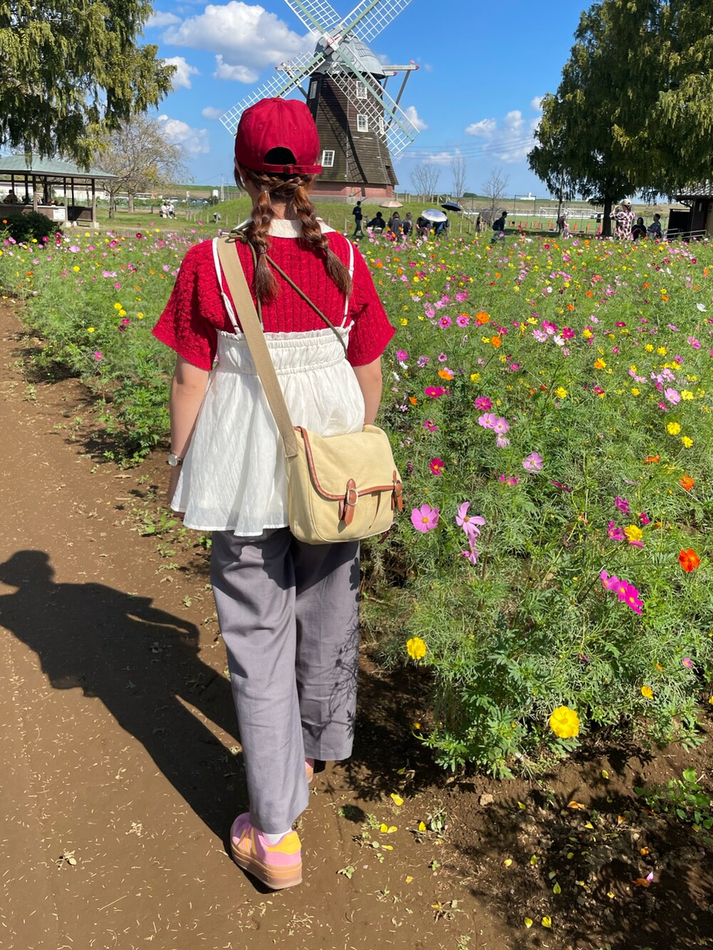 レッド系のトップス、ホワイト系のその他トップス、グレー系のスラックスを着用したレディースの秋コーディネートの2枚目の写真