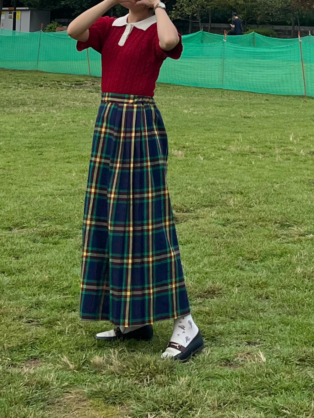 レッド系のトップス、グリーン系のスカート、その他のパンプスを着用したレディースの秋コーディネートの2枚目の写真