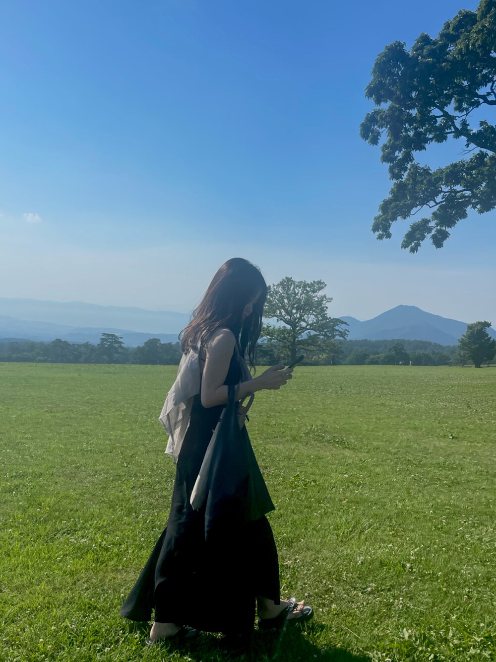 ブラック系のトップス、ブラック系のサンダルを着用したレディースの春コーディネートの2枚目の写真