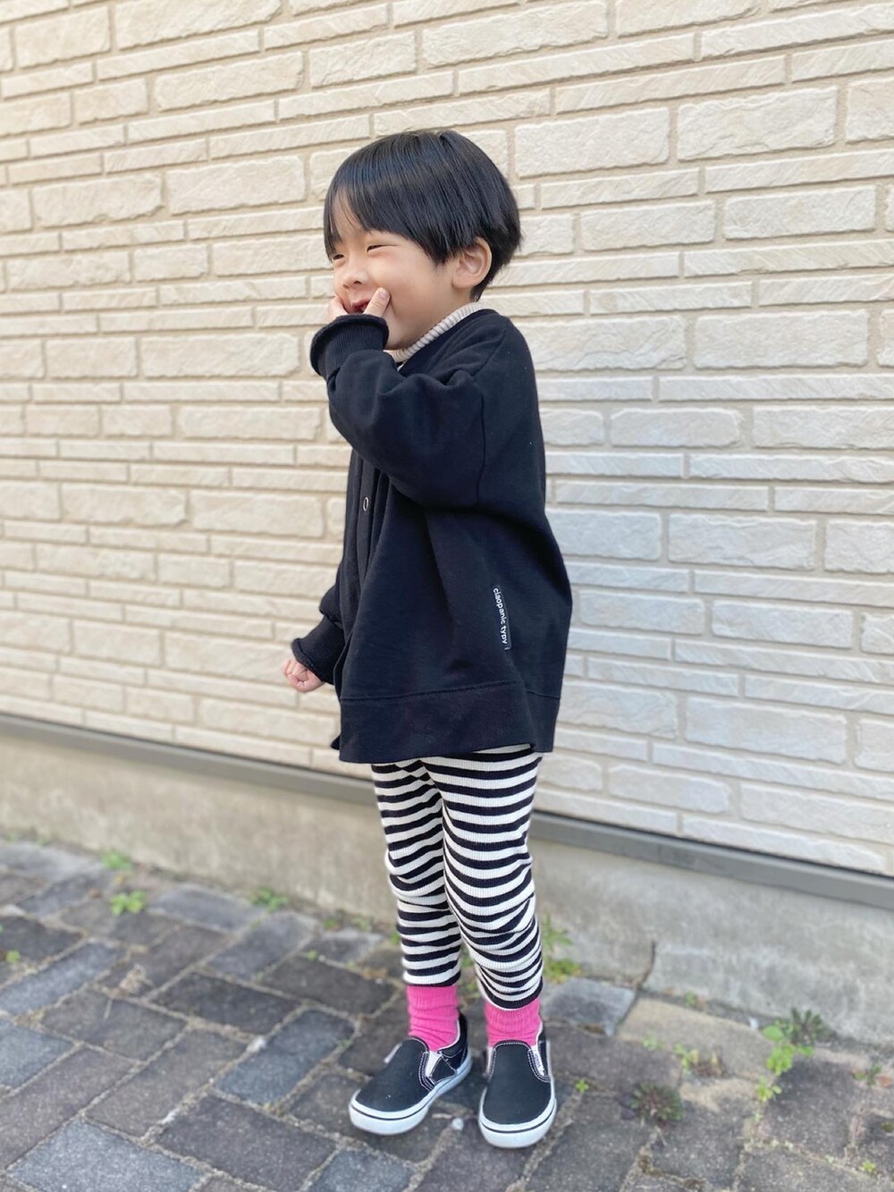 ブラック系のスニーカー、ブラック系のカーディガン/ボレロ、ホワイト系のニット/セーターを着用したキッズの冬コーディネートの2枚目の写真