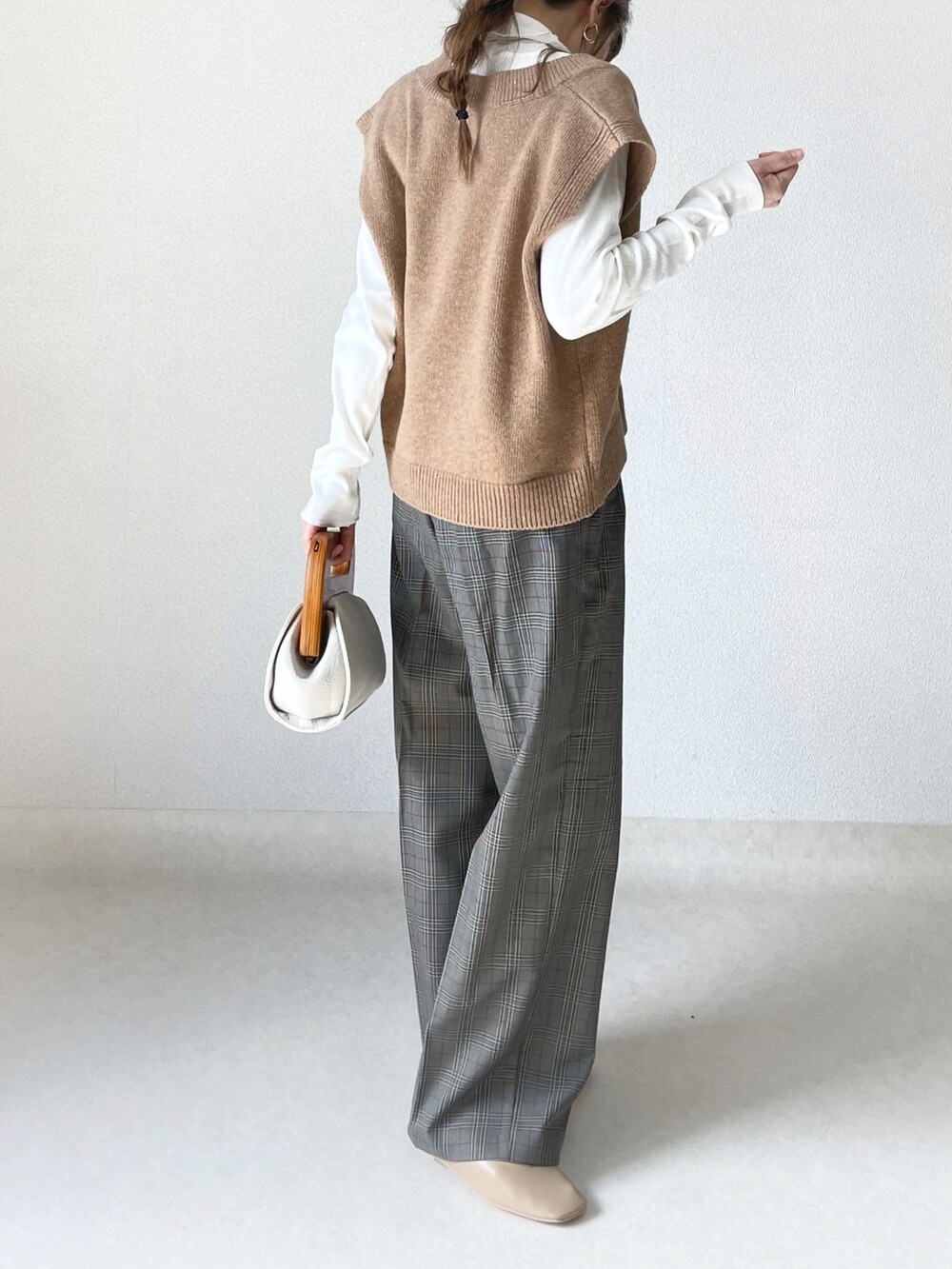 ホワイト系のクラッチバッグ、グレー系のパンツ、ベージュ系のパンプスを着用したレディースの春コーディネートの4枚目の写真