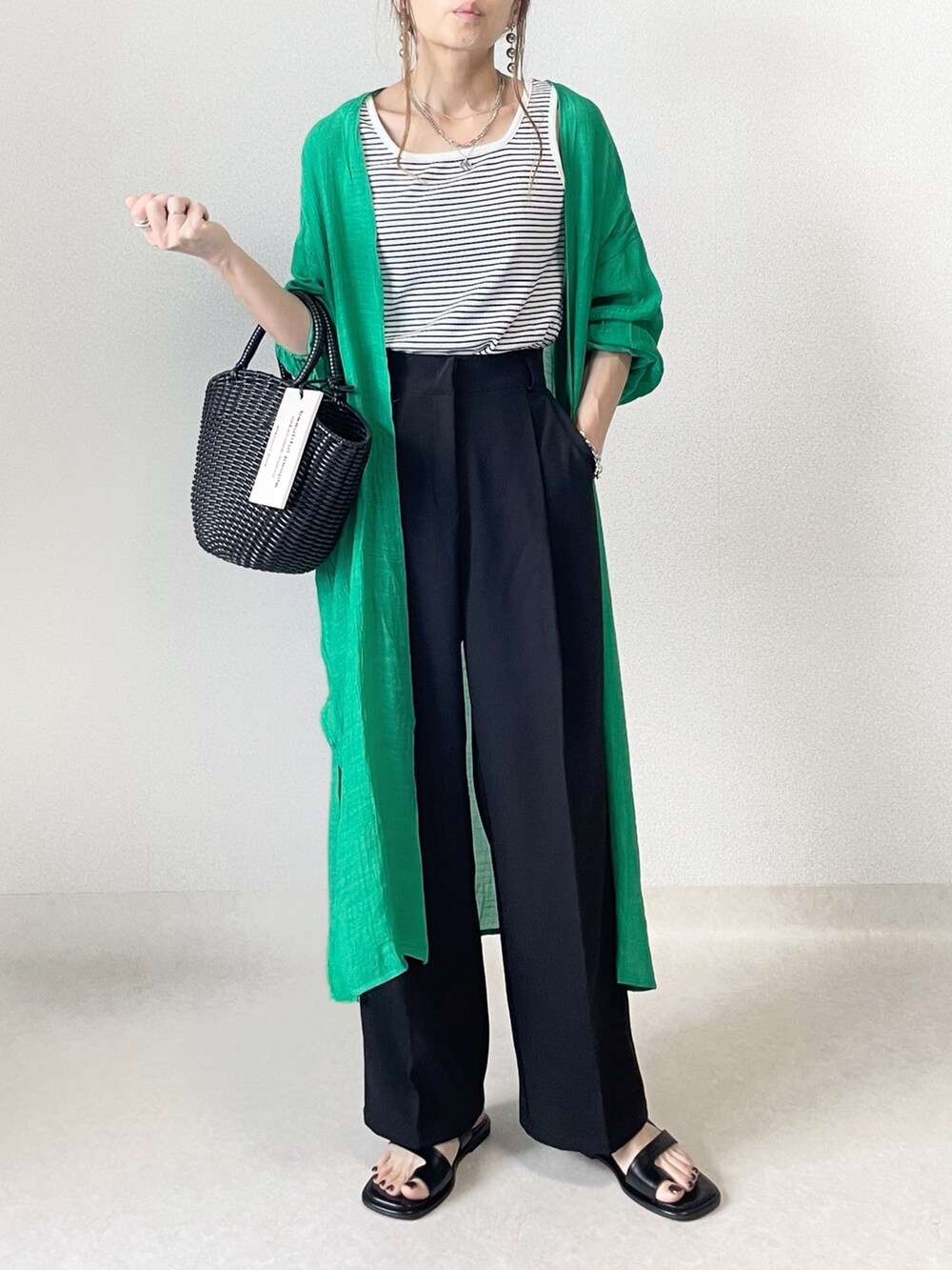 ホワイト系のタンクトップ、ブラック系のスラックス、ブラック系のハンドバッグを着用したレディースの春コーディネートの4枚目の写真