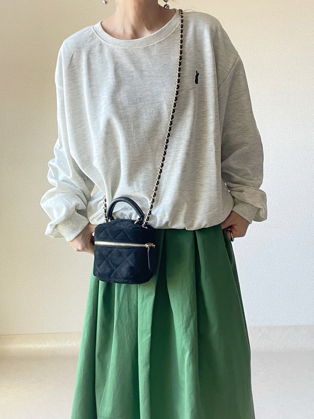 ベージュ系のスウェット、グリーン系のスカート、ブラック系のショルダーバッグを着用したレディースの春コーディネートの3枚目の写真