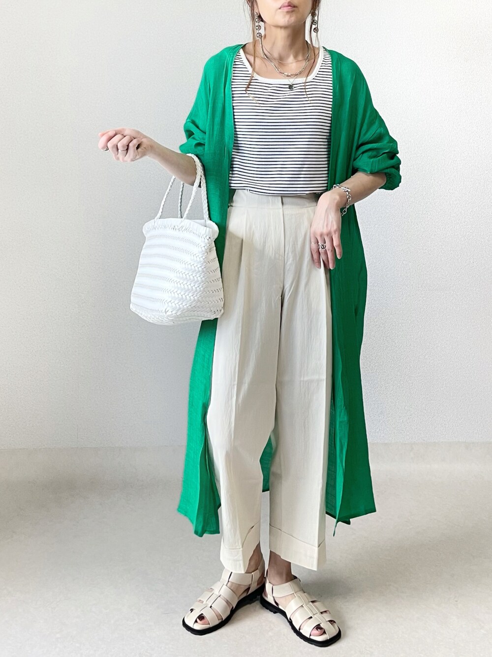 ホワイト系のタンクトップ、ブラック系のスラックス、ブラック系のハンドバッグを着用したレディースの春コーディネートの2枚目の写真