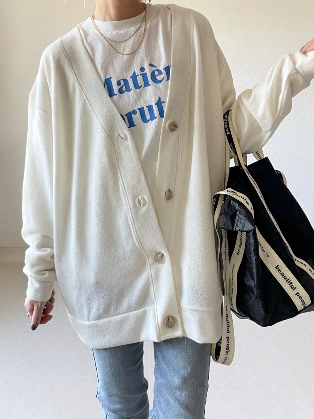 ホワイト系のカーディガン/ボレロ、ホワイト系のTシャツ/カットソー、ブラック系のトートバッグを着用したレディースの春コーディネートの3枚目の写真