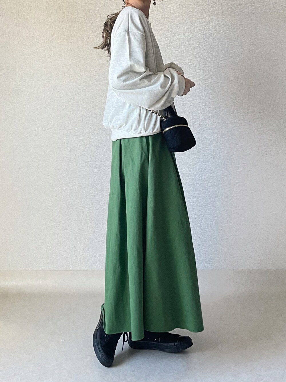 ベージュ系のスウェット、グリーン系のスカート、ブラック系のショルダーバッグを着用したレディースの春コーディネートの2枚目の写真