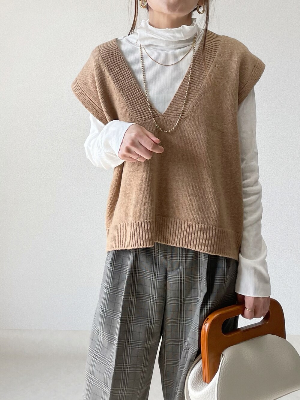 ホワイト系のクラッチバッグ、グレー系のパンツ、ベージュ系のパンプスを着用したレディースの春コーディネートの5枚目の写真