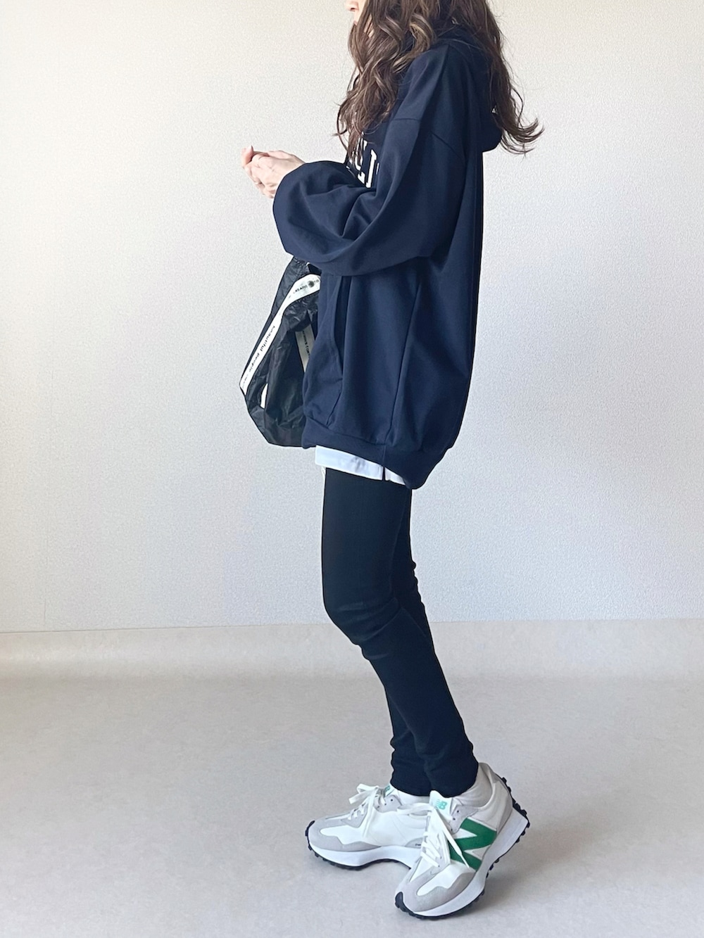 ブルー系のパーカー、ホワイト系のスカート、ブラック系のトートバッグを着用したレディースの秋コーディネートの4枚目の写真