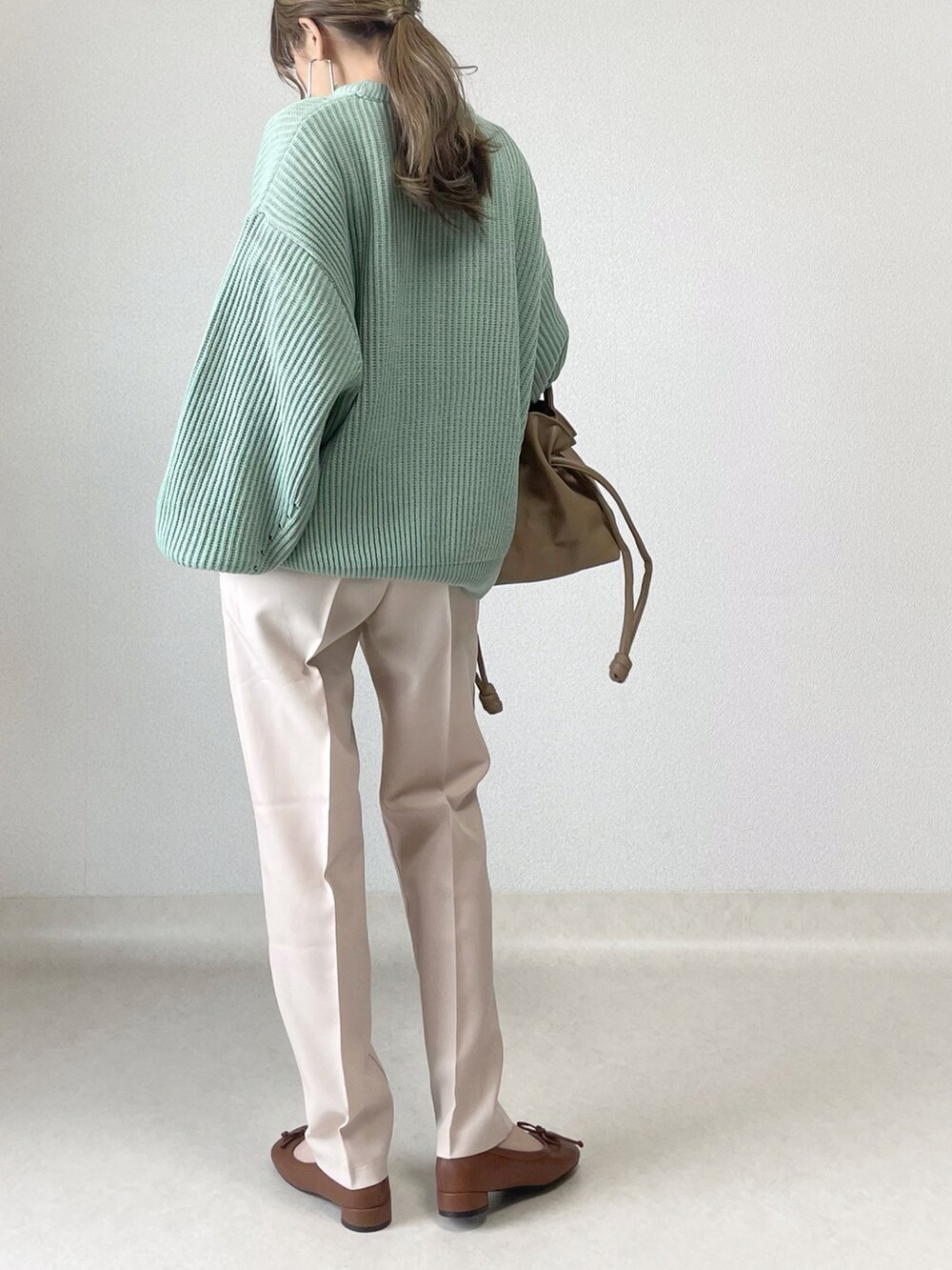 グリーン系のニット/セーター、ベージュ系のスラックス、ブラウン系のその他シューズを着用したレディースの春コーディネートの3枚目の写真