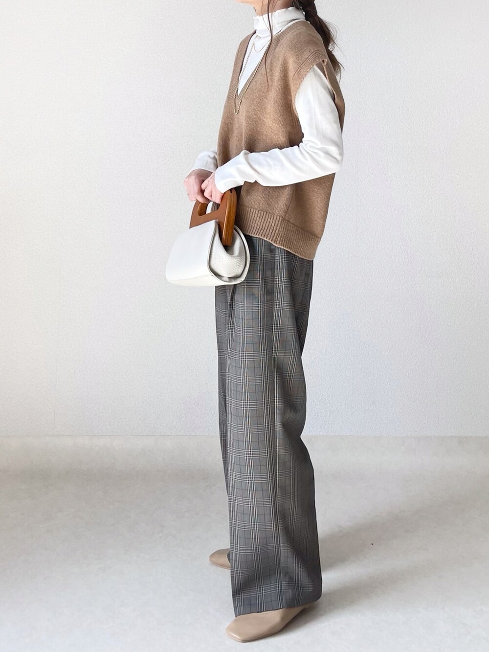 ホワイト系のクラッチバッグ、グレー系のパンツ、ベージュ系のパンプスを着用したレディースの春コーディネートの3枚目の写真