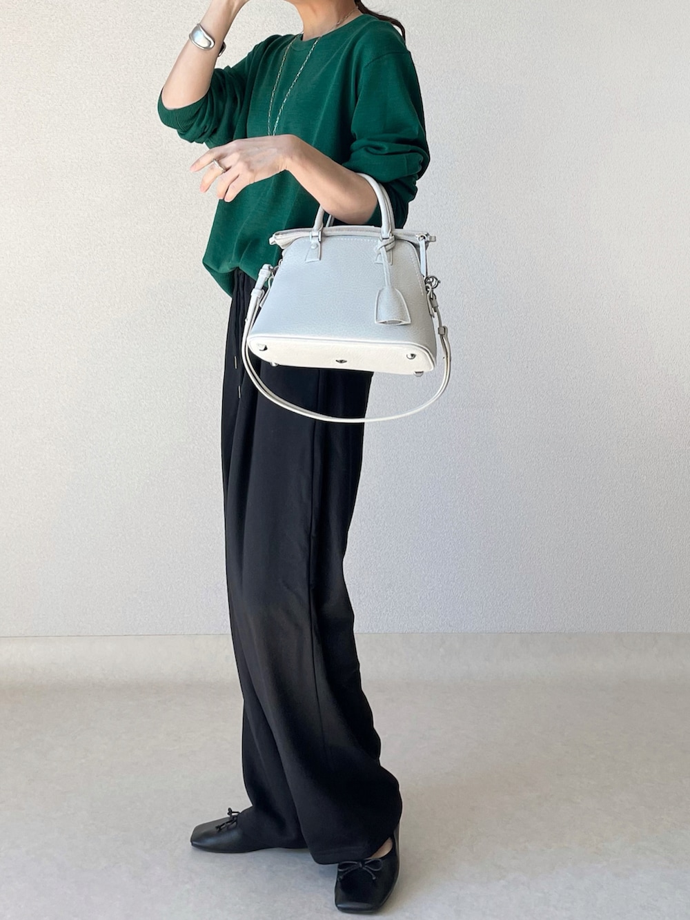 グリーン系のニット/セーター、ブラック系のスウェットパンツ、ブラック系のバレエシューズを着用したレディースの秋コーディネートの2枚目の写真