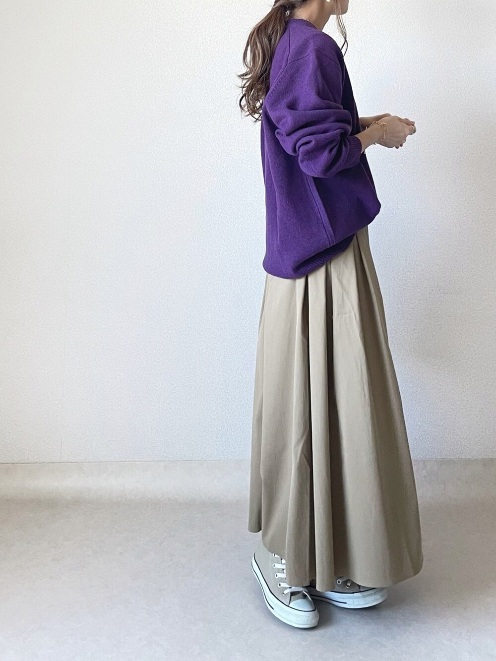 パープル系のニット/セーター、ベージュ系のスカートを着用したレディースの秋コーディネートの2枚目の写真