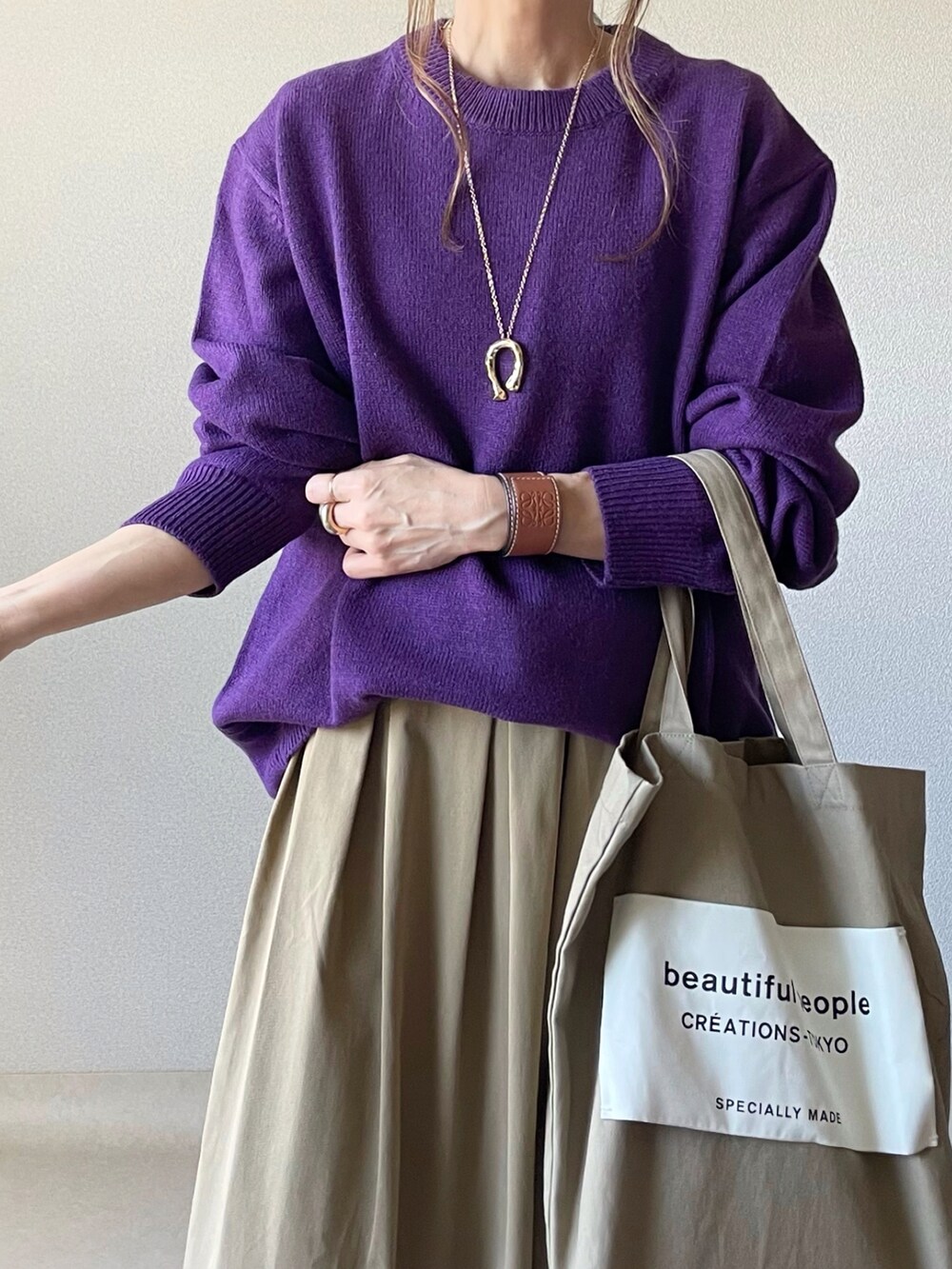 パープル系のニット/セーター、ベージュ系のスカートを着用したレディースの秋コーディネートの4枚目の写真