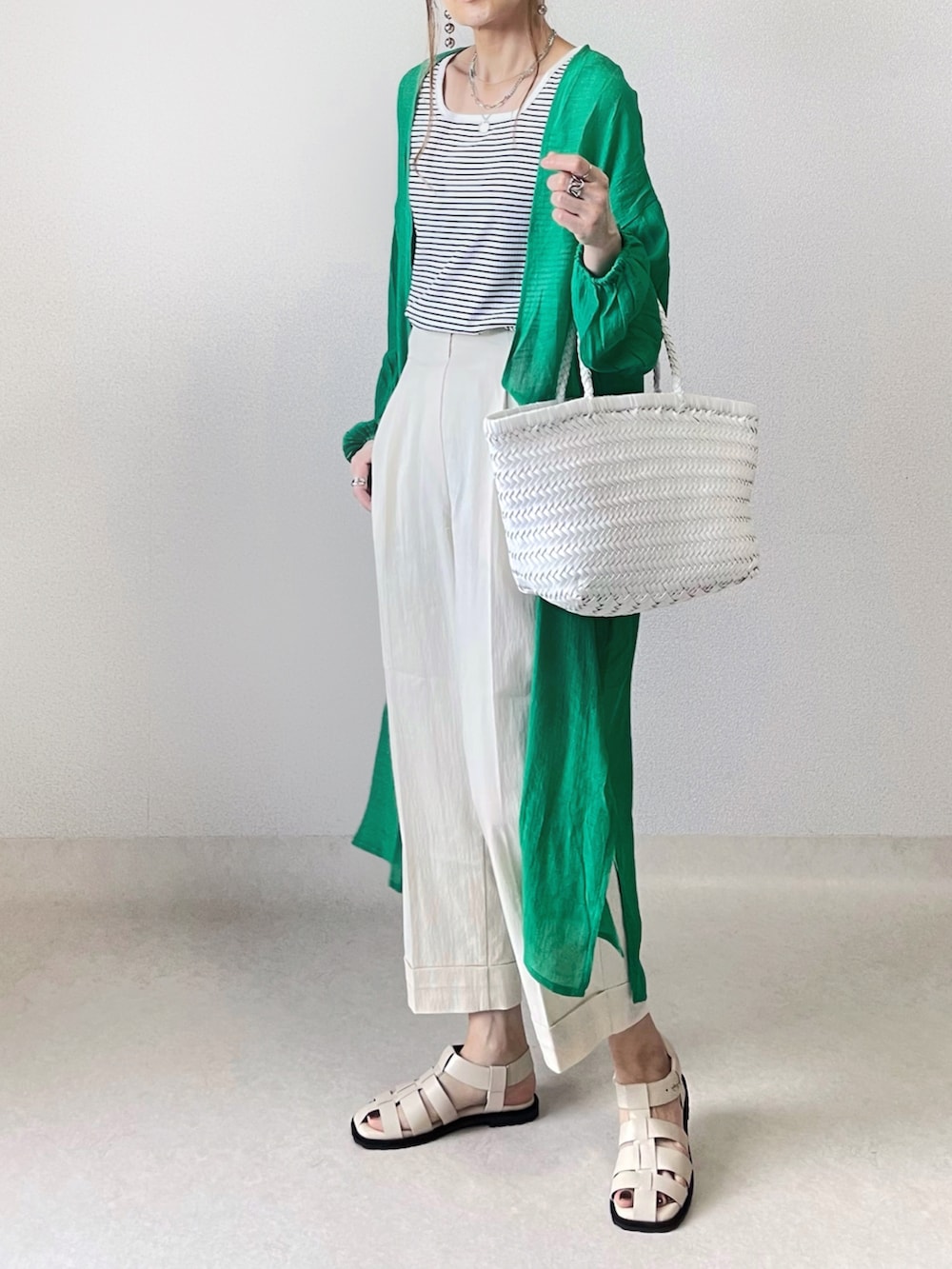 ホワイト系のタンクトップ、ブラック系のスラックス、ブラック系のハンドバッグを着用したレディースの春コーディネートの3枚目の写真