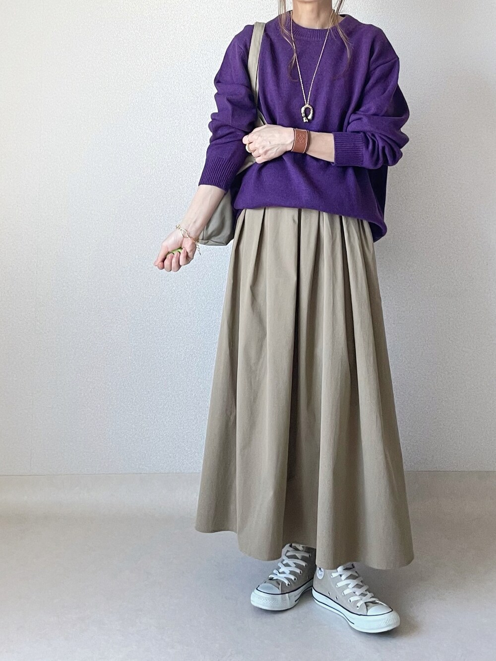 パープル系のニット/セーター、ベージュ系のスカートを着用したレディースの秋コーディネートの3枚目の写真