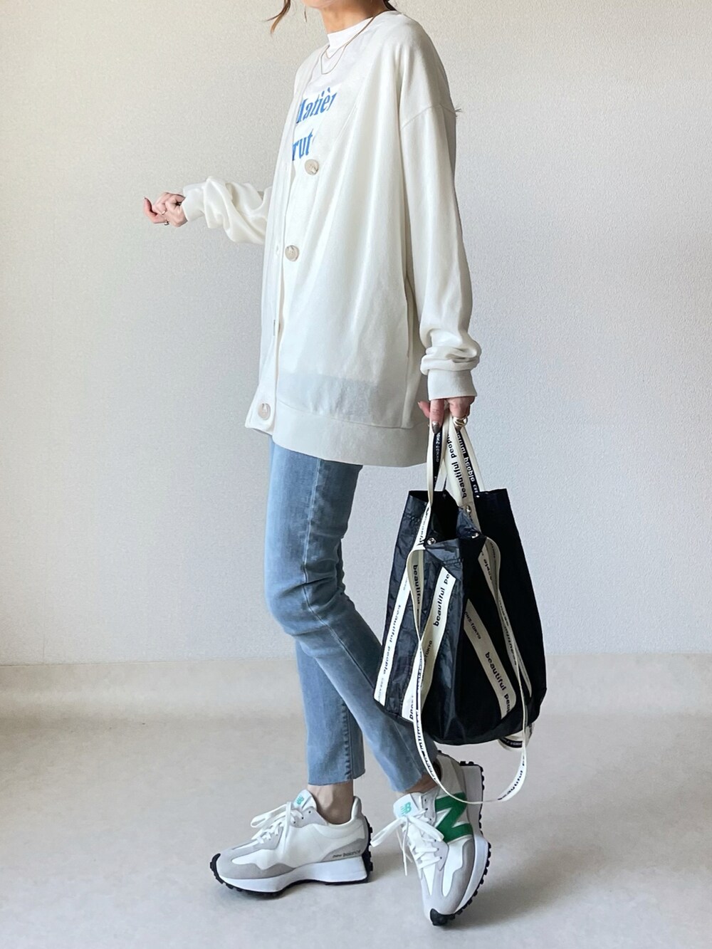 ホワイト系のカーディガン/ボレロ、ホワイト系のTシャツ/カットソー、ブラック系のトートバッグを着用したレディースの春コーディネートの2枚目の写真