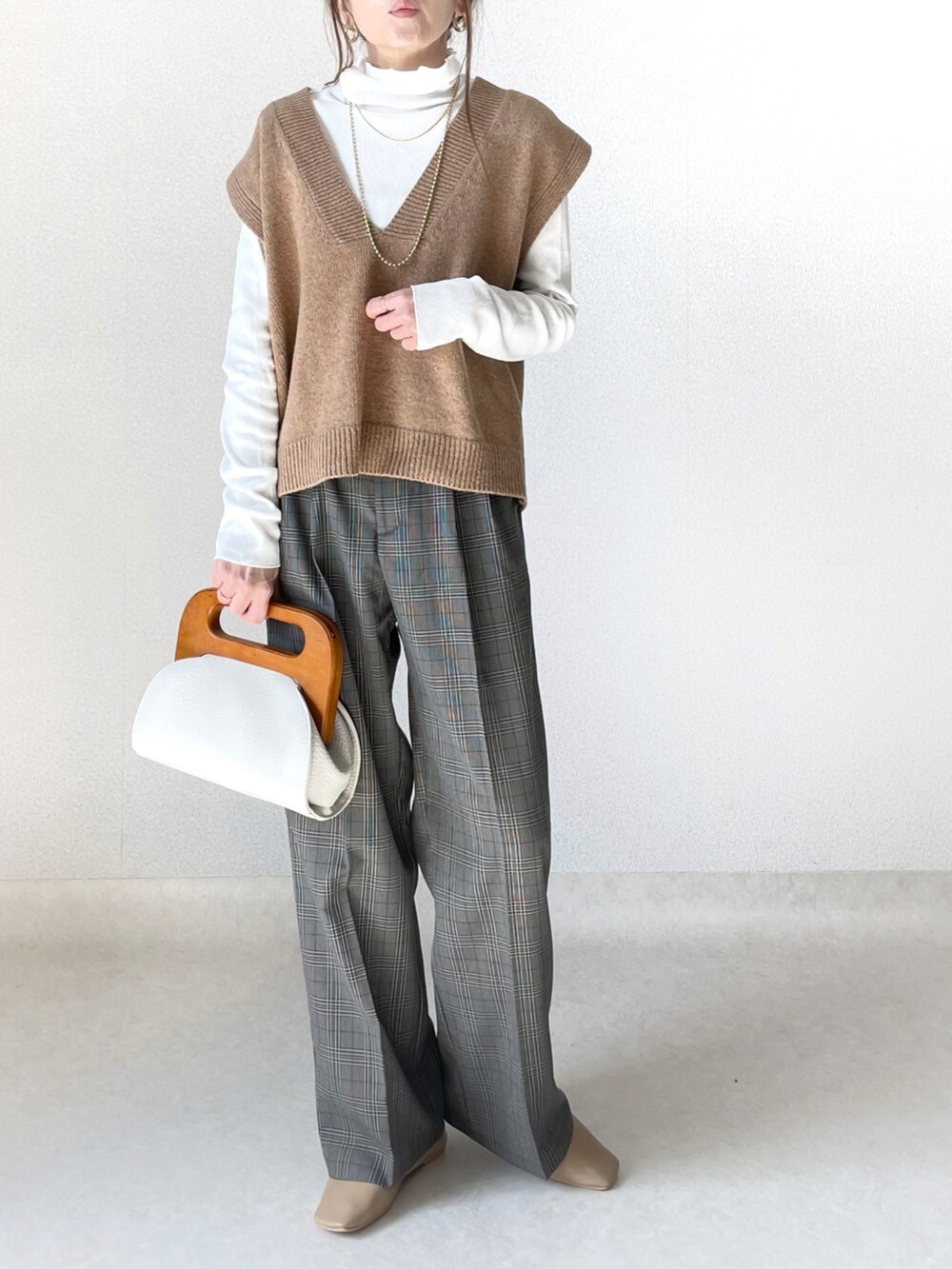 ホワイト系のクラッチバッグ、グレー系のパンツ、ベージュ系のパンプスを着用したレディースの春コーディネートの2枚目の写真