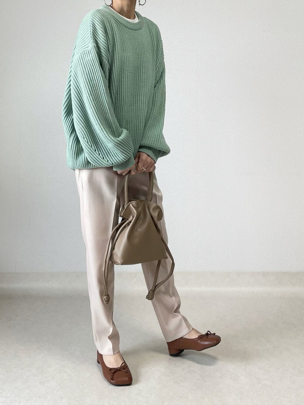 グリーン系のニット/セーター、ベージュ系のスラックス、ブラウン系のその他シューズを着用したレディースの春コーディネートの2枚目の写真