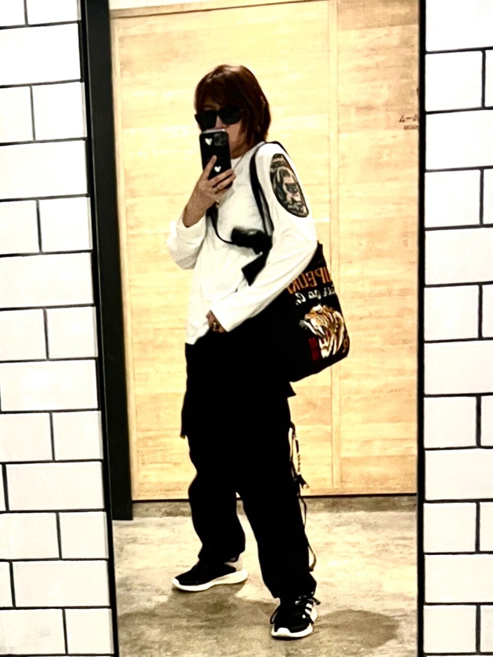 ブラック系のトートバッグ、ホワイト系のTシャツ/カットソー、ブラック系のスニーカーを着用したレディースの春コーディネートの2枚目の写真