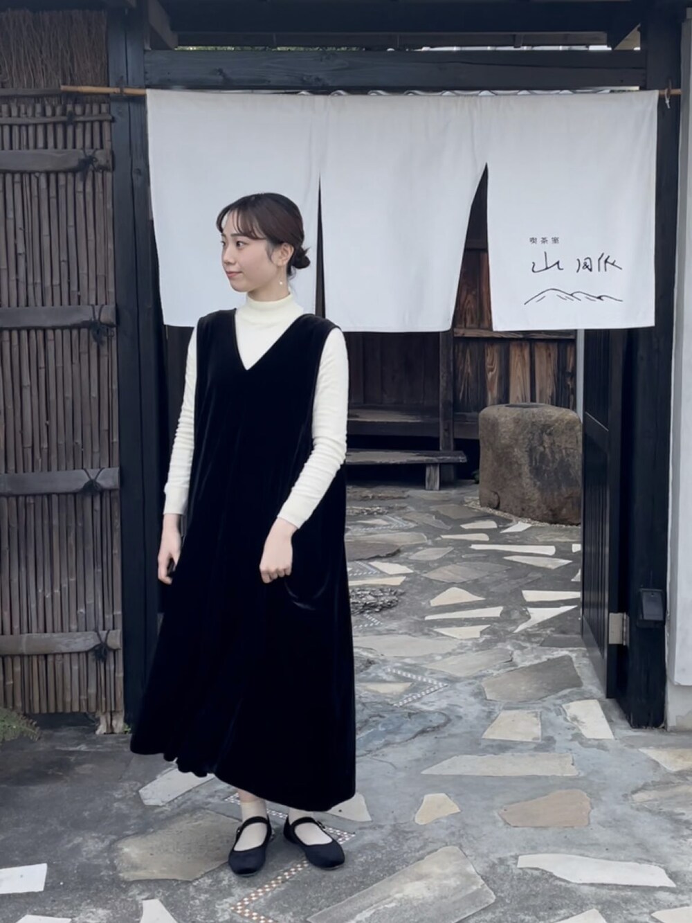 ブラック系のバレエシューズ、ブラック系のワンピース、ホワイト系のニット/セーターを着用したレディースの冬コーディネートの2枚目の写真