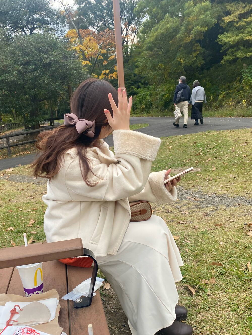 ホワイト系のムートンコート、ブラウン系のブーツ、ベージュ系のショルダーバッグを着用したレディースの秋コーディネートの3枚目の写真