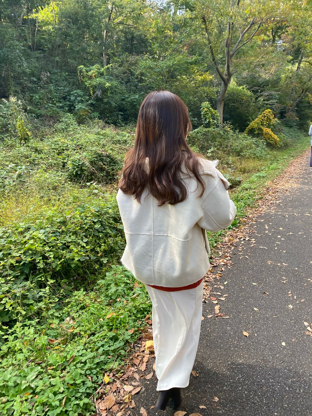 ホワイト系のムートンコート、ブラウン系のブーツ、ベージュ系のショルダーバッグを着用したレディースの秋コーディネートの4枚目の写真