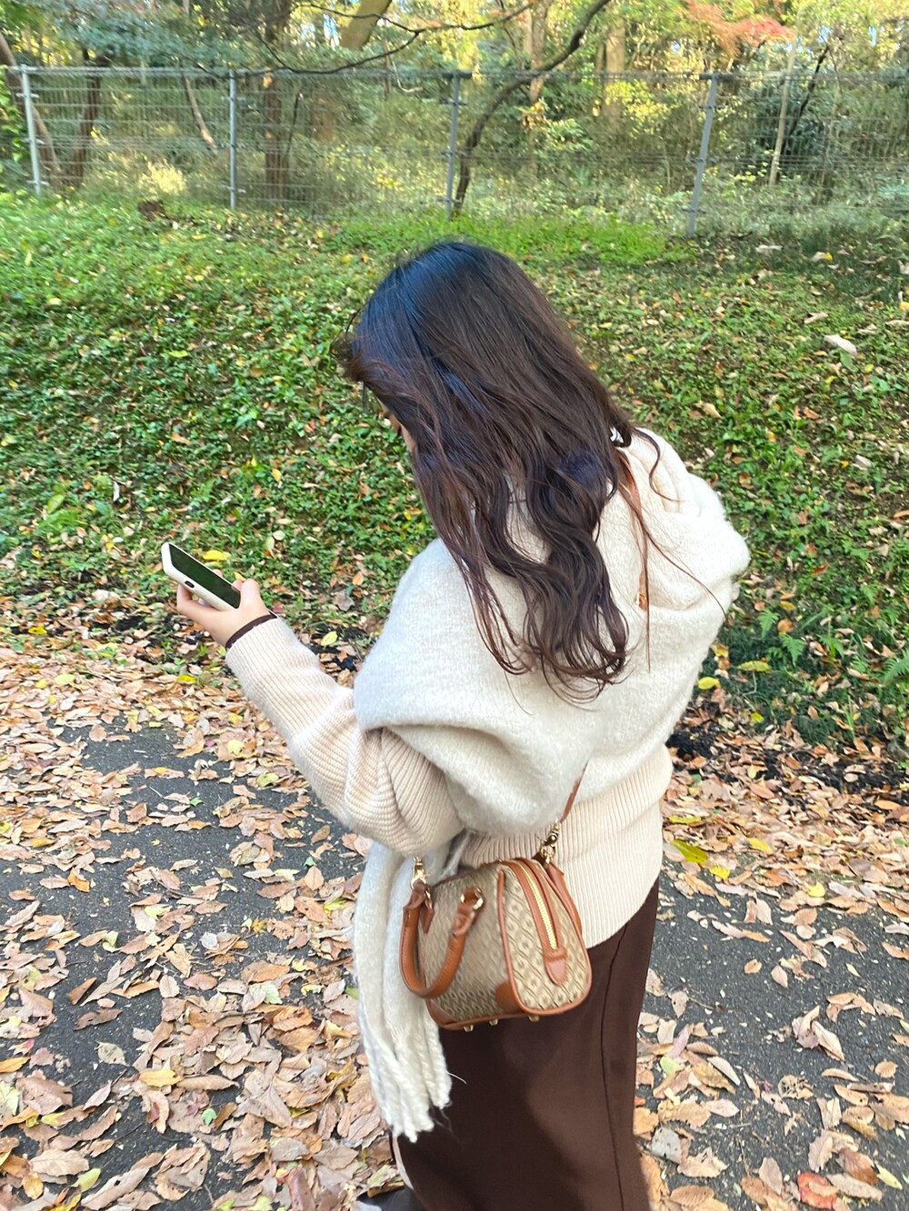 ベージュ系のショルダーバッグ、ホワイト系のニット/セーター、ブラウン系のワンピース/ドレスを着用したレディースの秋コーディネートの2枚目の写真