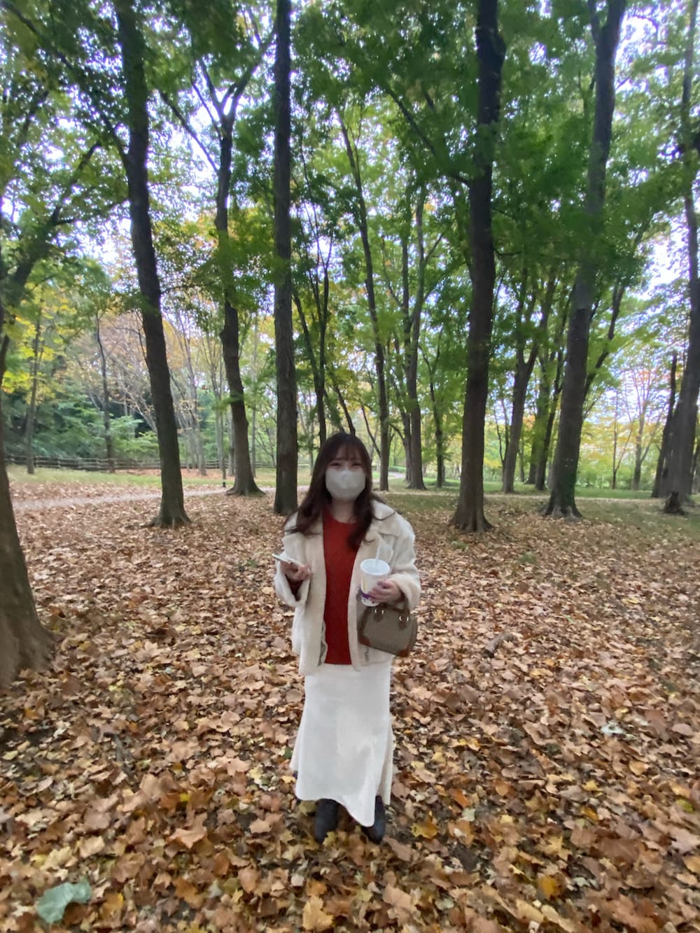 ホワイト系のムートンコート、ブラウン系のブーツ、ベージュ系のショルダーバッグを着用したレディースの秋コーディネートの2枚目の写真