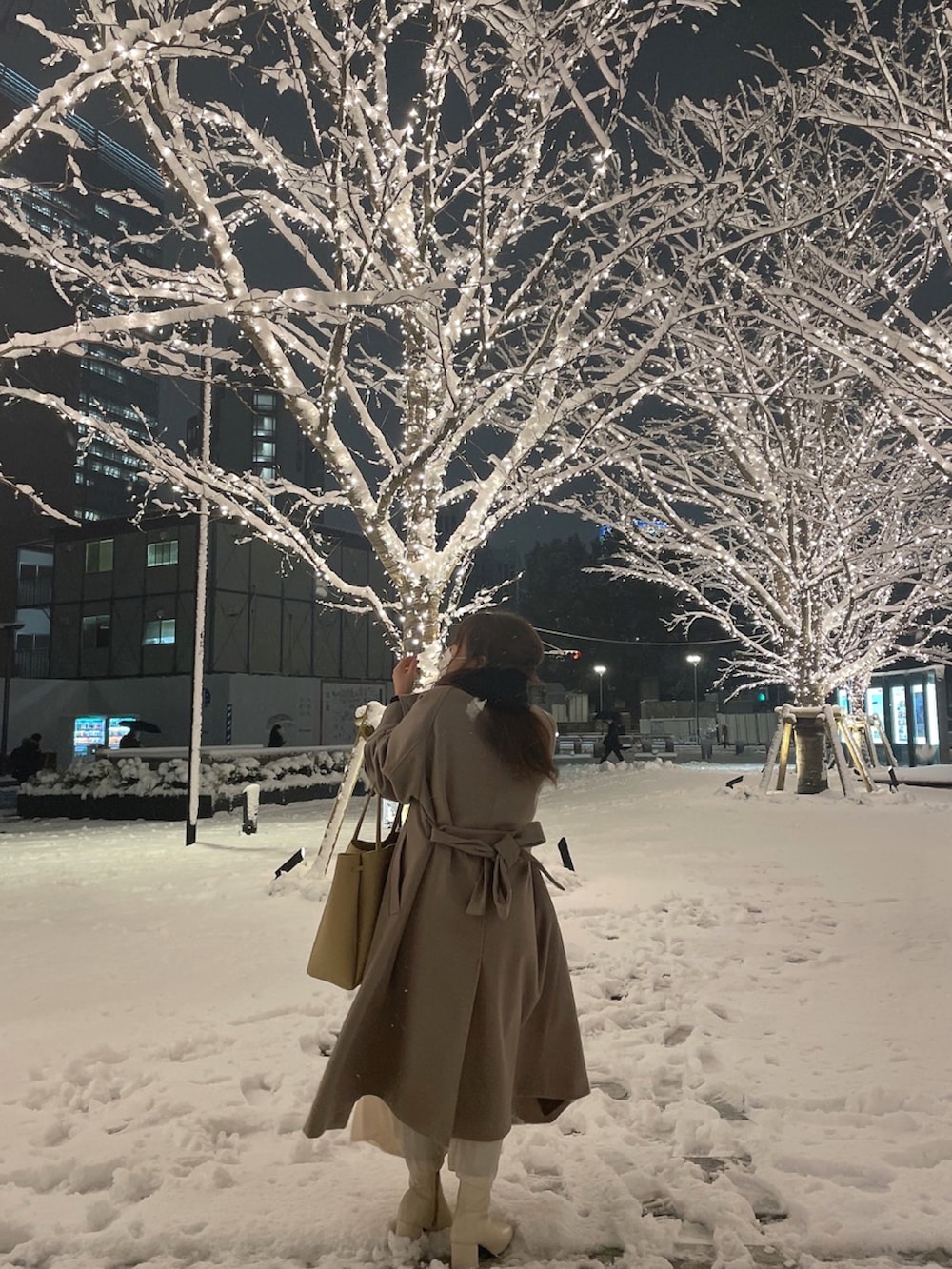 ベージュ系のステンカラーコート、ホワイト系のスカート、ホワイト系のブーツを着用したレディースの冬コーディネートの2枚目の写真