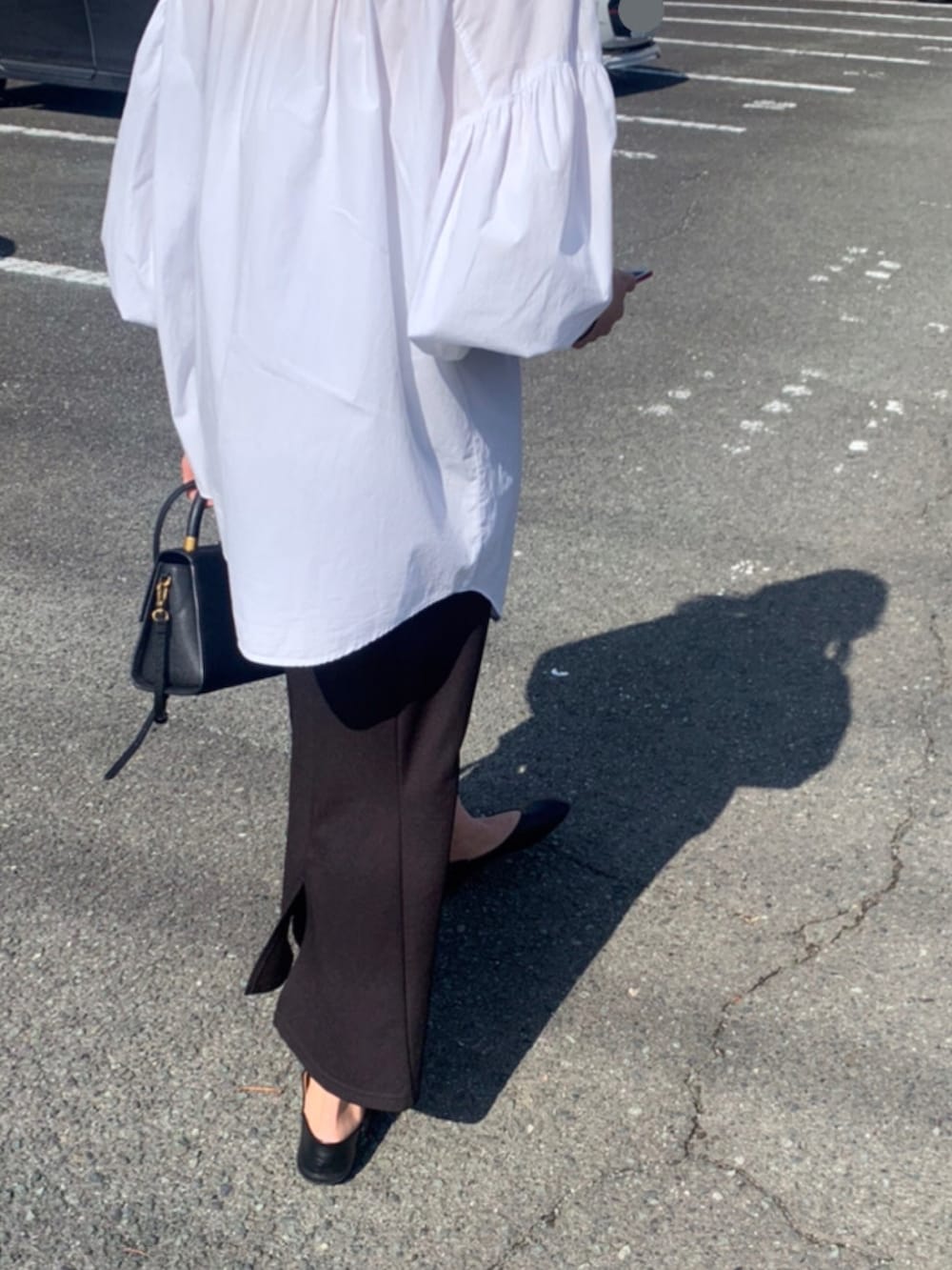ブラック系のハンドバッグ、ブラック系のスカートを着用したレディースの春コーディネートの2枚目の写真