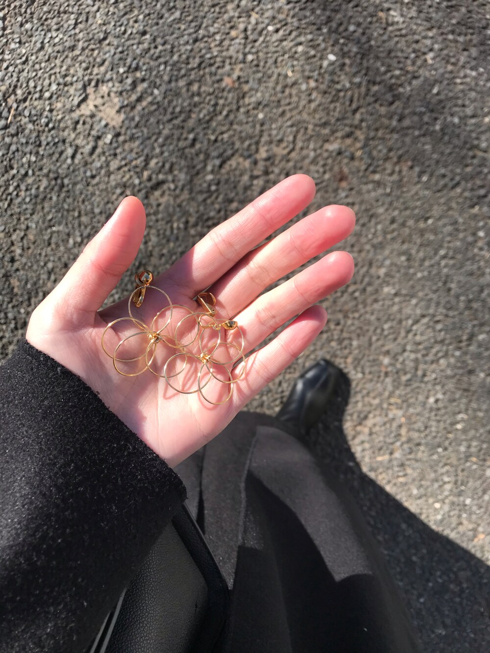 ブラック系のノーカラーコート、ブラック系のハンドバッグ、ホワイト系のニット/セーターを着用したレディースの冬コーディネートの2枚目の写真