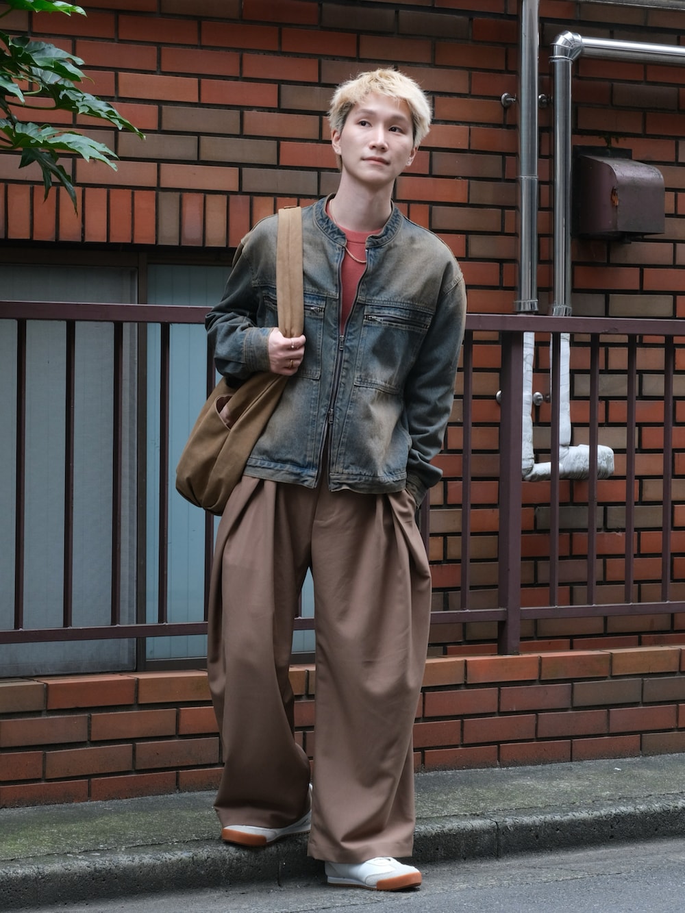 ブルー系のデニムジャケット、ブラウン系のスラックス、レッド系のニット/セーターを着用したメンズの秋コーディネートの5枚目の写真