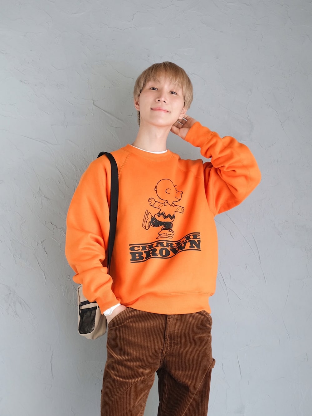 ホワイト系のスニーカー、ブラウン系のパンツ、オレンジ系のスウェットを着用したメンズの秋コーディネートの2枚目の写真