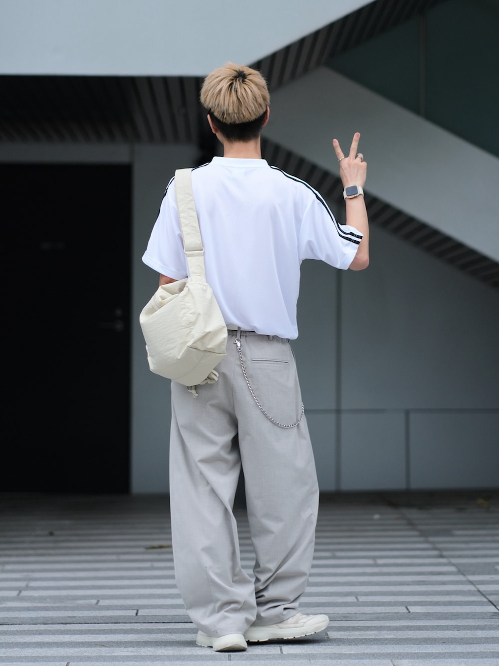 ホワイト系のTシャツ/カットソー、グレー系のスラックス、ホワイト系のスニーカーを着用したメンズの夏コーディネートの4枚目の写真