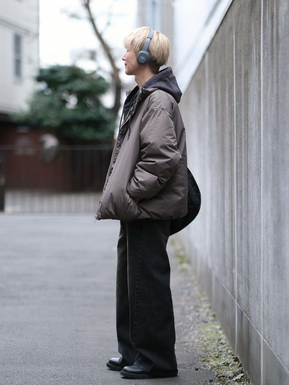 ブラウン系のダウンジャケット/コート、ブラック系のデニムパンツ、ブラック系のショルダーバッグを着用したメンズの冬コーディネートの4枚目の写真