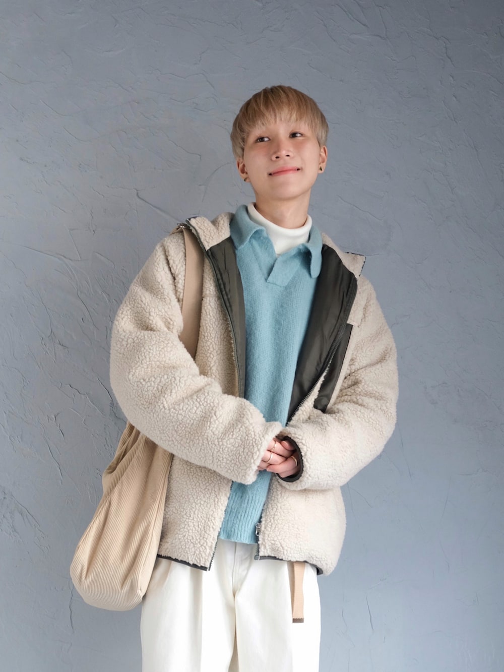 ベージュ系のショルダーバッグ、ブルー系のニット/セーター、ベージュ系のブルゾンを着用したメンズの冬コーディネートの2枚目の写真