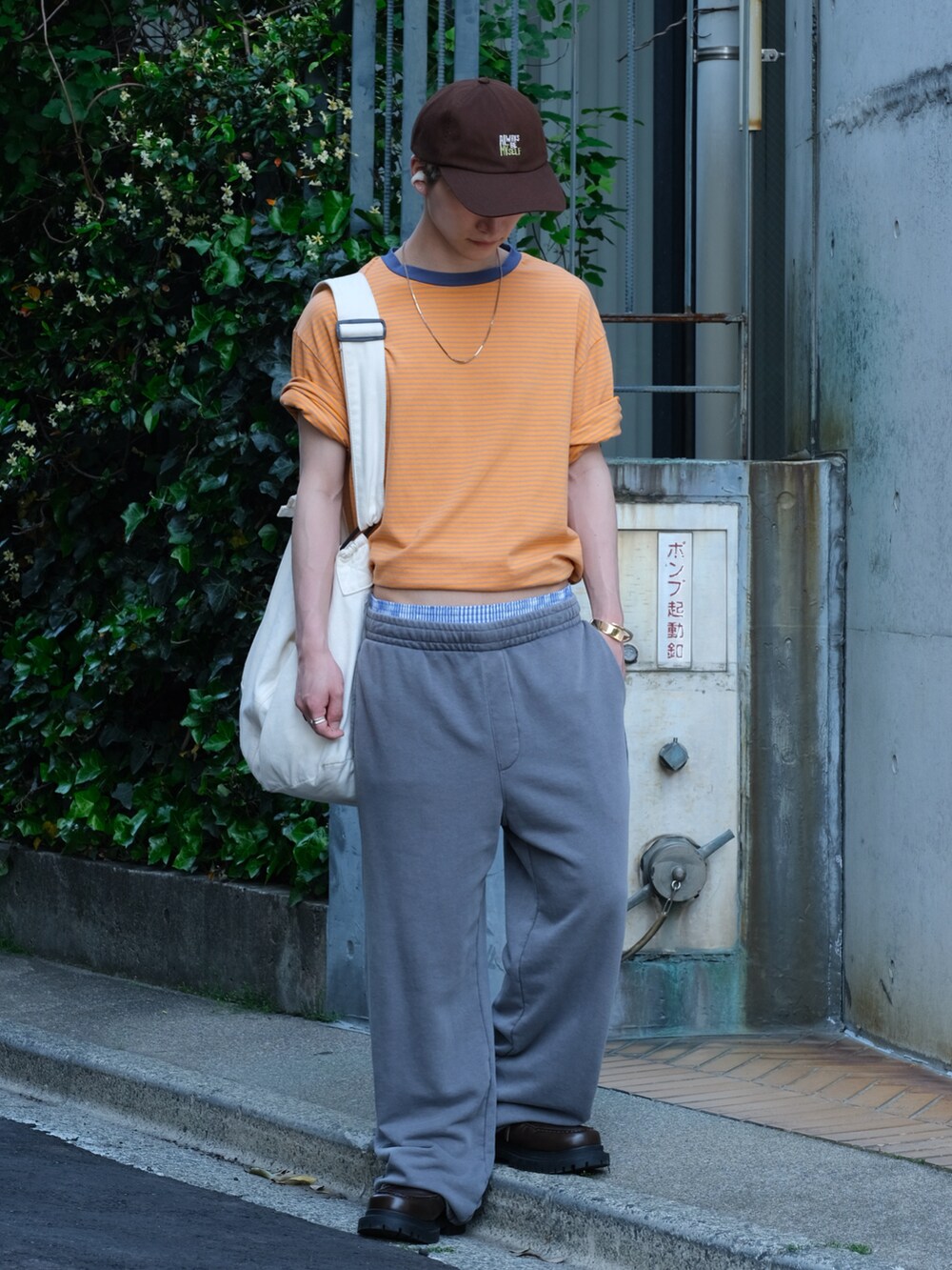 グレー系のスウェットパンツ、オレンジ系のTシャツ/カットソー、ブラウン系のシューズを着用したメンズの春コーディネートの2枚目の写真