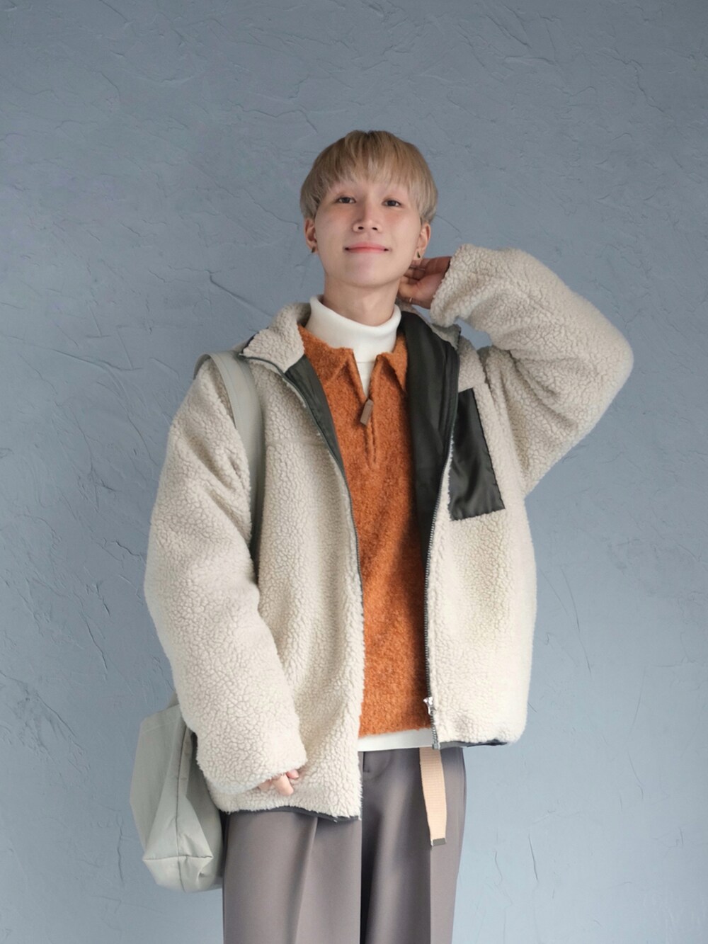 グレー系のスニーカー、ベージュ系のブルゾン、オレンジ系のニット/セーターを着用したメンズの冬コーディネートの2枚目の写真