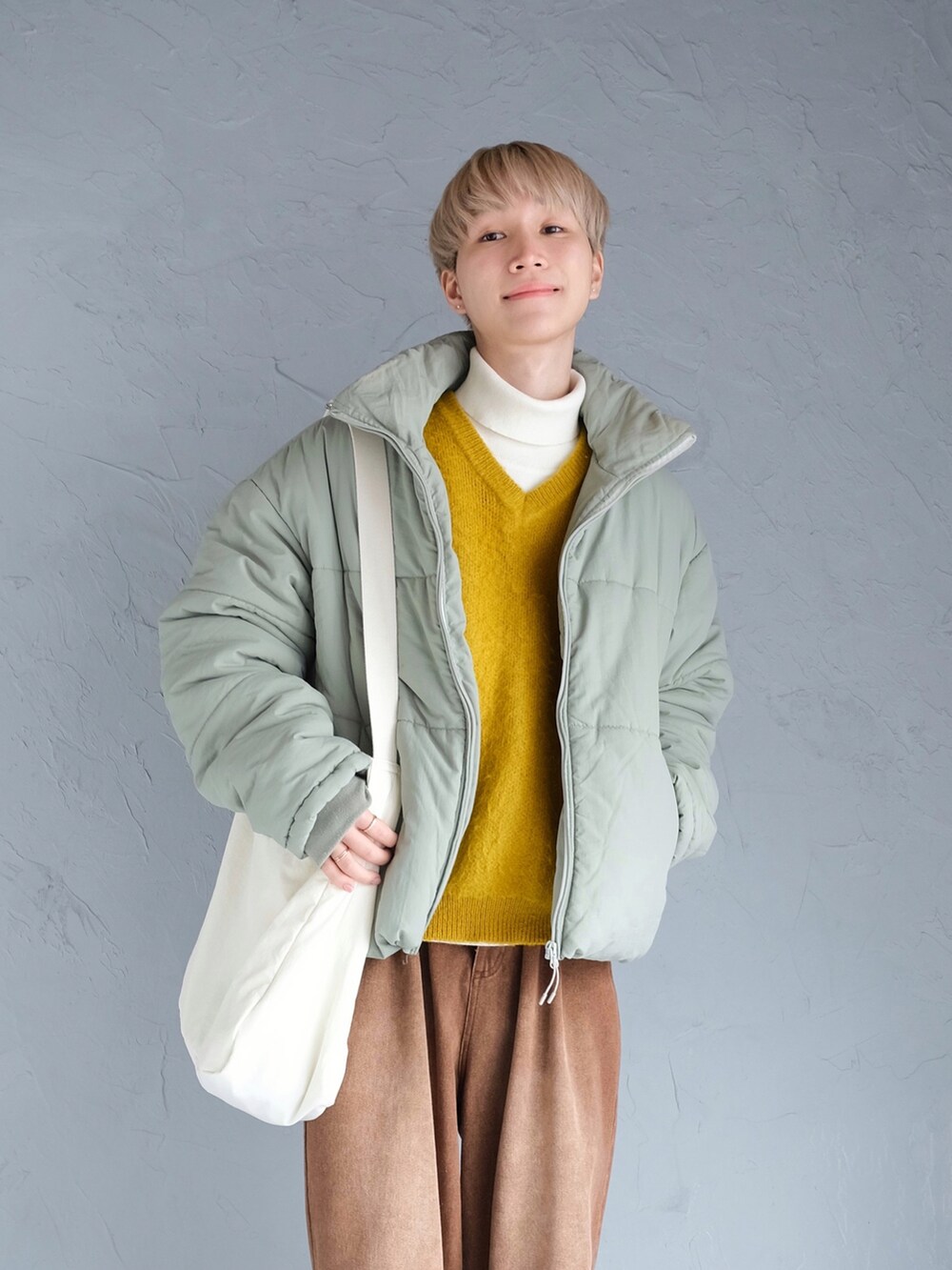 ブラウン系のデニムパンツ、ホワイト系のショルダーバッグ、グリーン系のその他アウターを着用したメンズの冬コーディネートの2枚目の写真