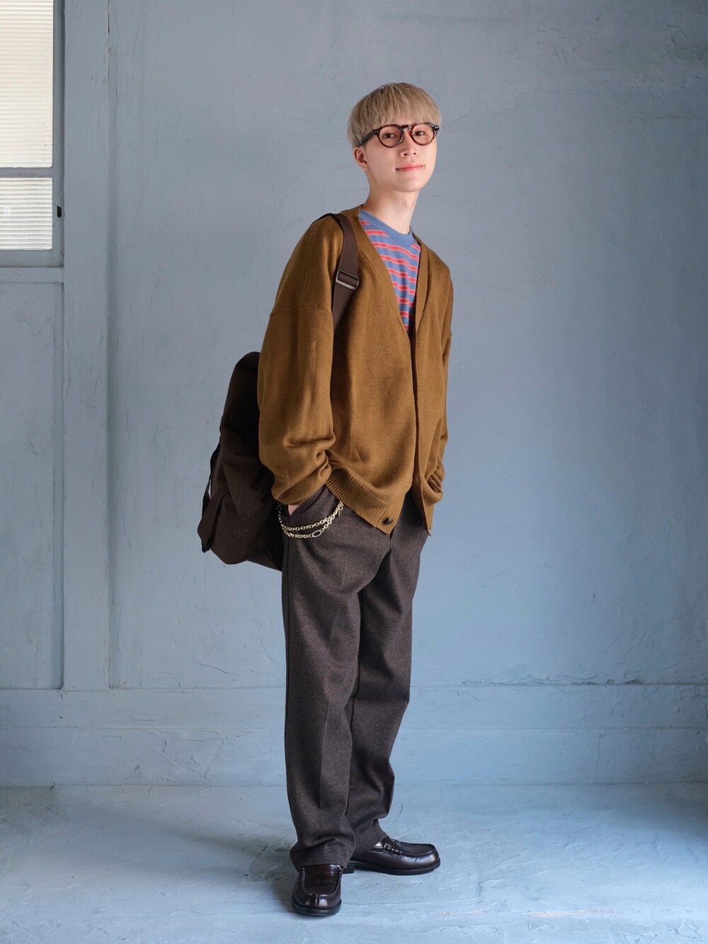 ブルー系のTシャツ/カットソー、イエロー系のカーディガン/ボレロ、ブラウン系のスラックスを着用したメンズの秋コーディネートの2枚目の写真