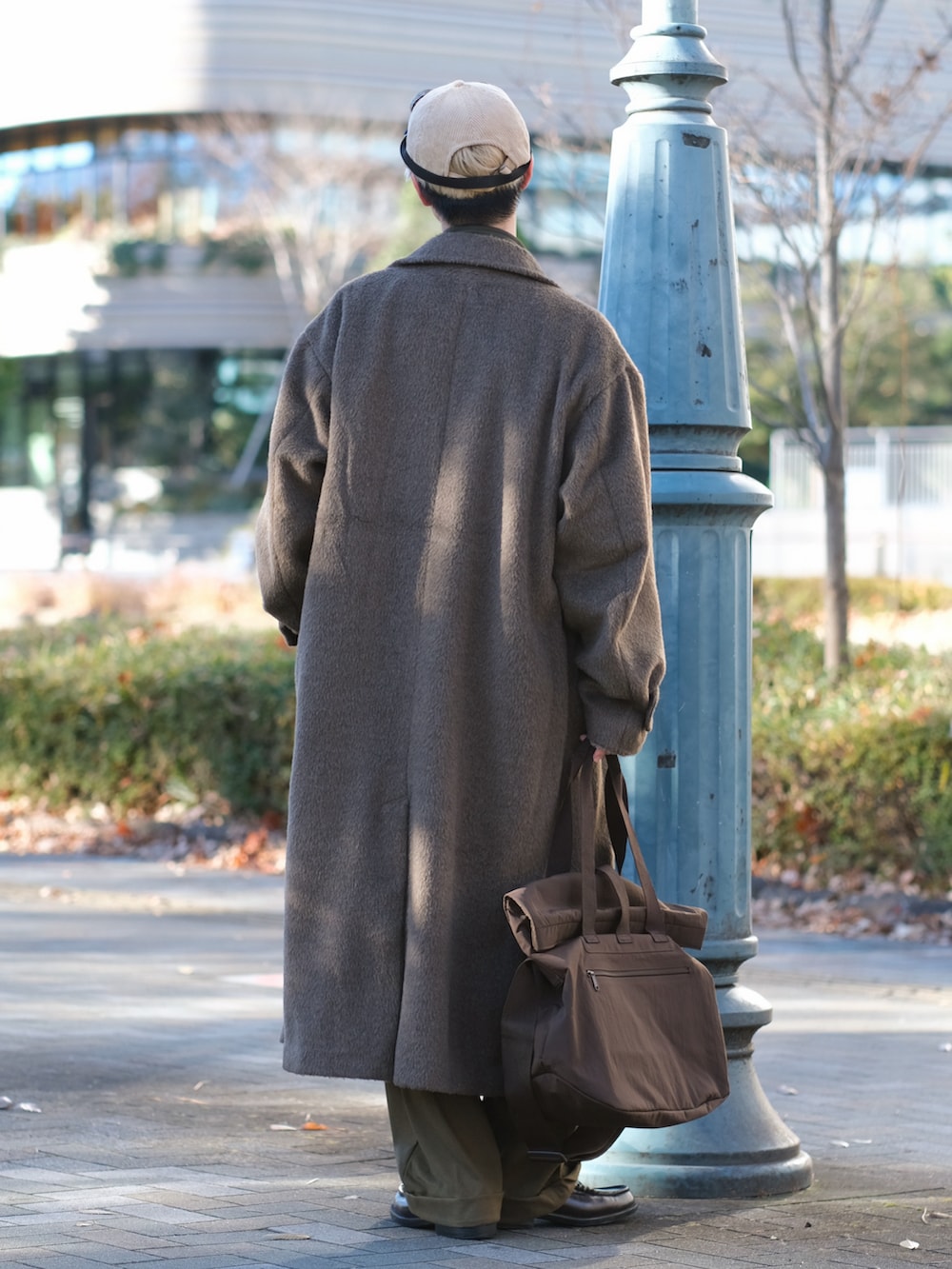 ブラウン系のチェスターコート、グリーン系のスウェットパンツ、ブラウン系のローファーを着用したメンズの冬コーディネートの4枚目の写真