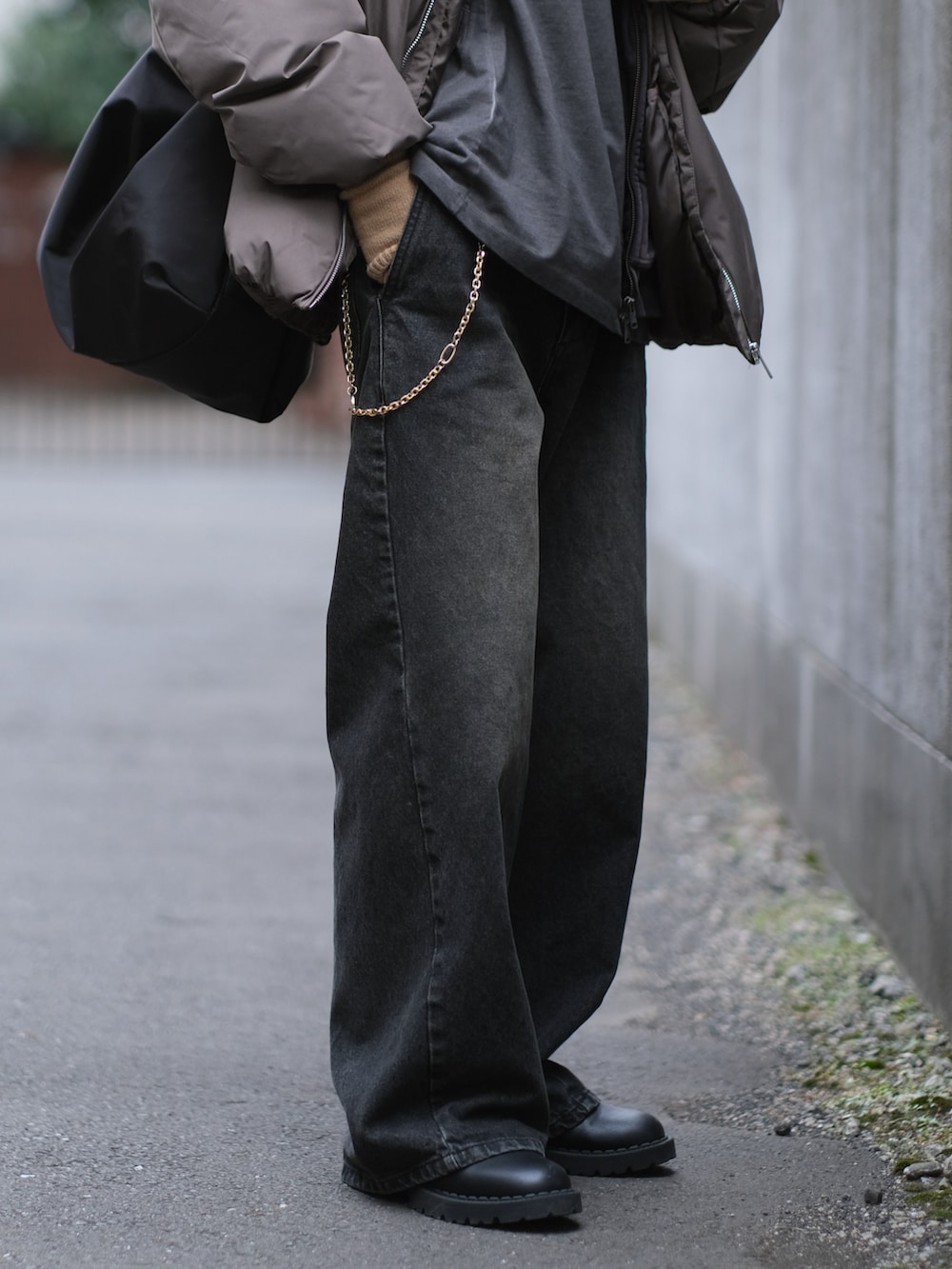 ブラウン系のダウンジャケット/コート、ブラック系のデニムパンツ、ブラック系のショルダーバッグを着用したメンズの冬コーディネートの3枚目の写真