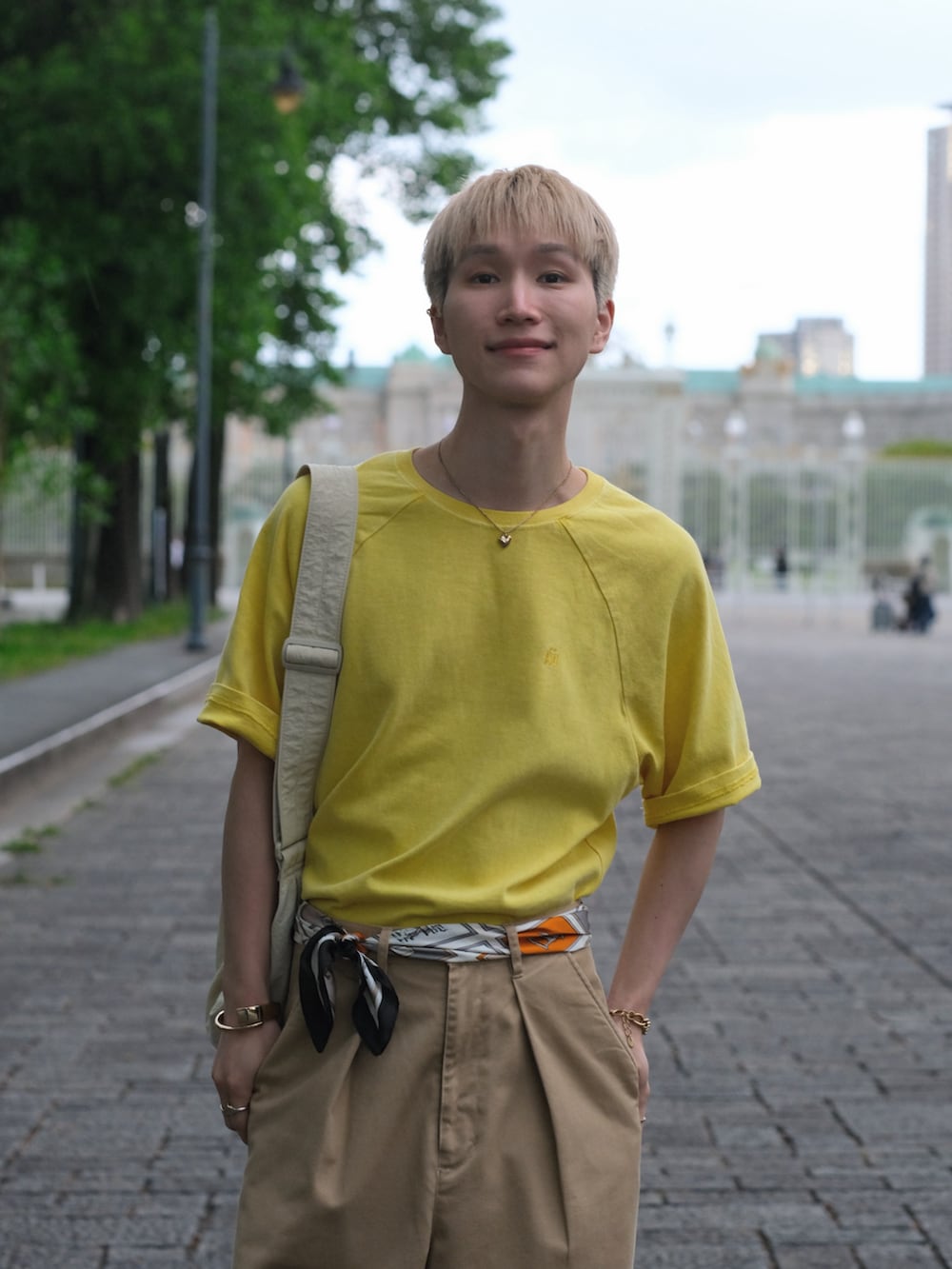 イエロー系のTシャツ/カットソー、ベージュ系のチノパンツ、ホワイト系のショルダーバッグを着用したメンズの夏コーディネートの2枚目の写真