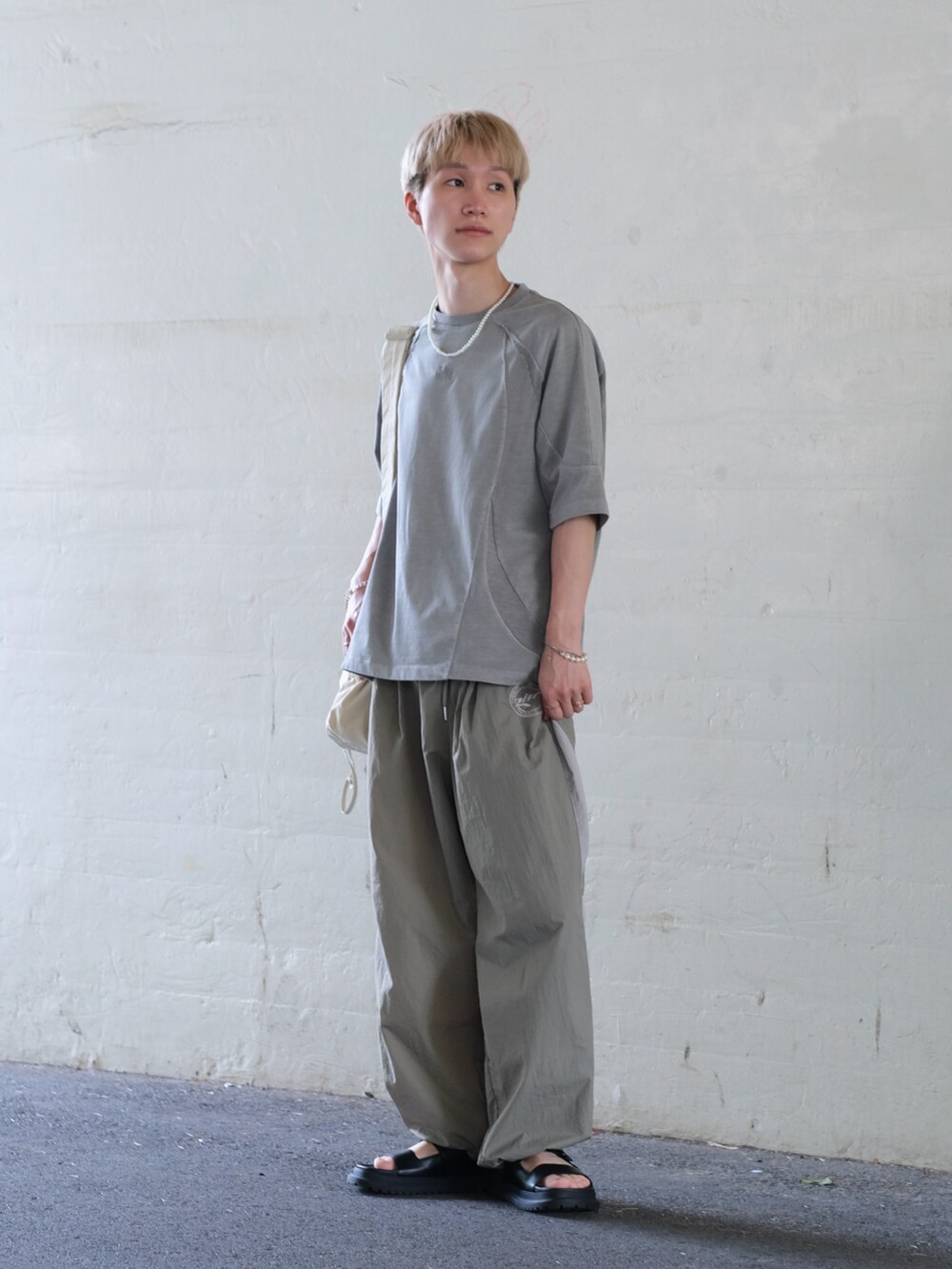 ベージュ系のその他パンツ、グレー系のTシャツ/カットソー、ホワイト系のショルダーバッグを着用したメンズの夏コーディネートの3枚目の写真