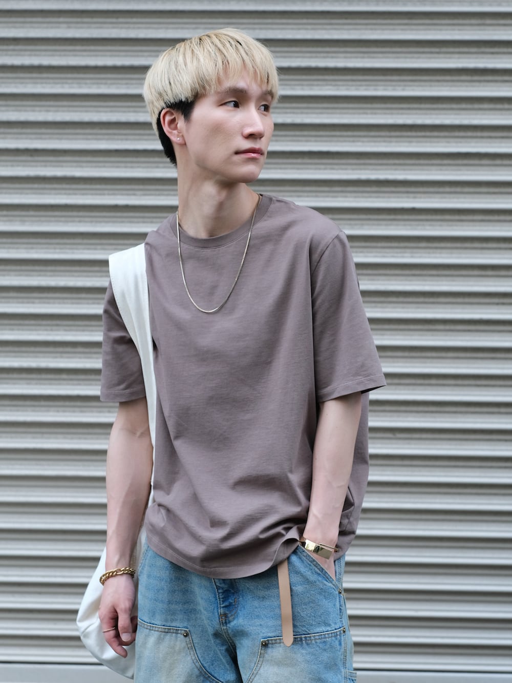 ブルー系のデニムパンツ、ブラウン系のTシャツ/カットソー、ホワイト系のショルダーバッグを着用したメンズの夏コーディネートの3枚目の写真